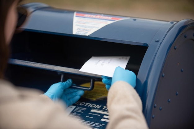 Zbliżenie osoby wkładającej list do skrzynki pocztowej