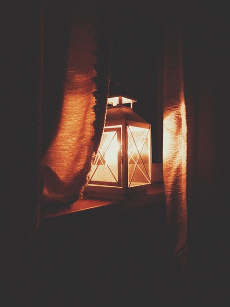 Zdjęcie zbliżenie oświetlonej lampy elektrycznej na stole w ciemnym pokoju