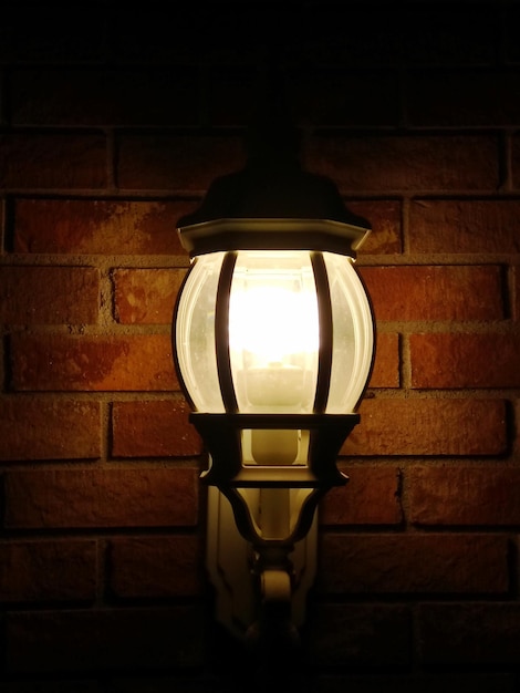Zbliżenie oświetlonej lampy na ceglanej ścianie