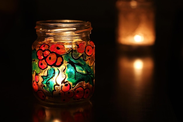 Zdjęcie zbliżenie oświetlonej świecy do herbaty na stole w ciemni