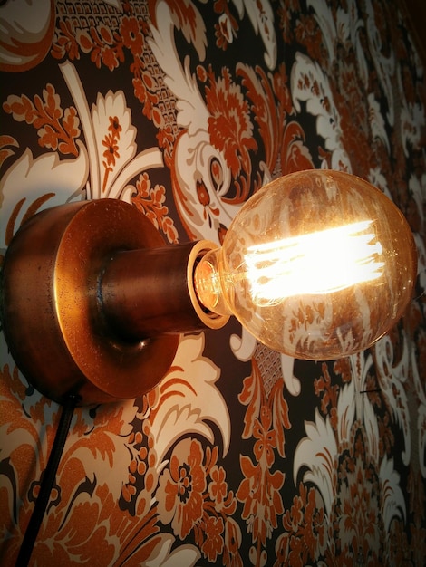 Zdjęcie zbliżenie oświetlonej żarówki na wzorowanej ścianie