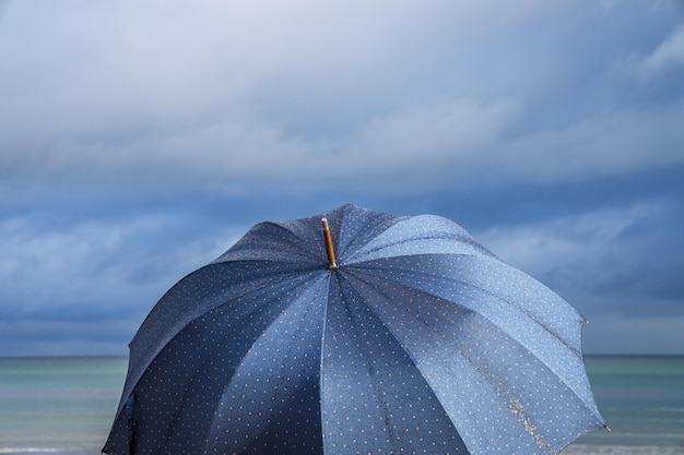 Zdjęcie zbliżenie otwartego parasola na chmurnym niebie na plaży