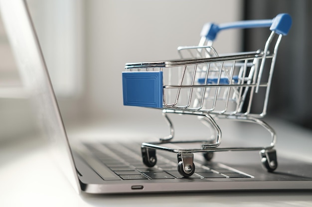 Zbliżenie ozdobnych wózków na zakupy, które znajdują się na klawiaturze laptopa Koncepcja sklepu internetowego