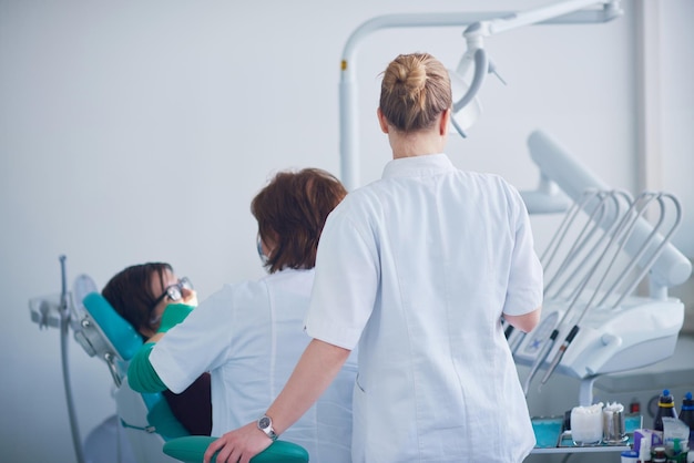 Zbliżenie pacjentki u dentysty czekającej na wizytę kontrolną z lekarzem w tle