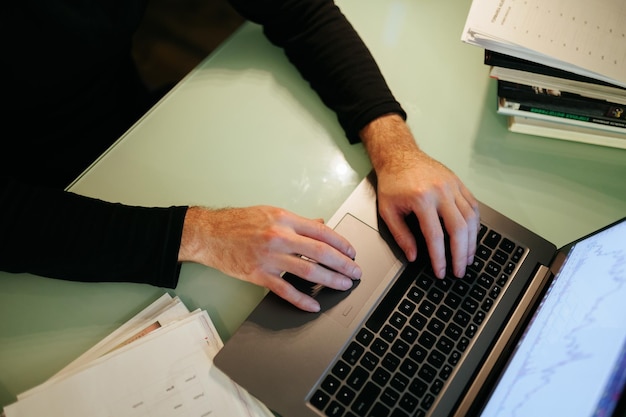 Zbliżenie pary rąk piszących na klawiaturze laptopa z widokiem górnym i touchpadem v