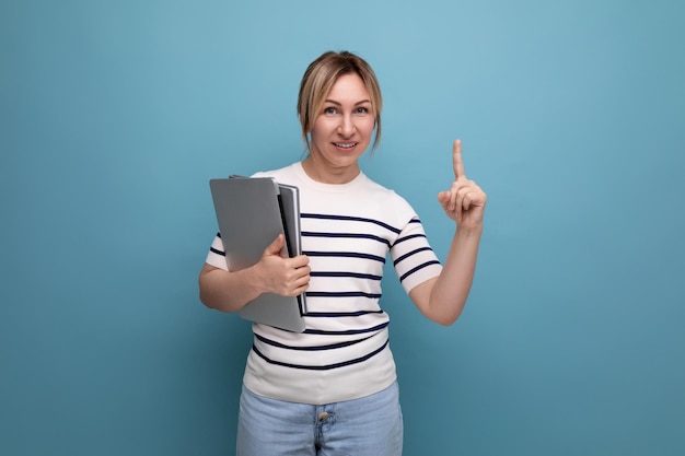 Zbliżenie pewnej blondynki w pasiastym swetrze trzymającej laptopa w dłoniach na niebiesko