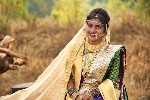 Zbliżenie pięknej indyjskiej panny młodej w tradycyjnym saree pozującej na świeżym powietrzu w parku