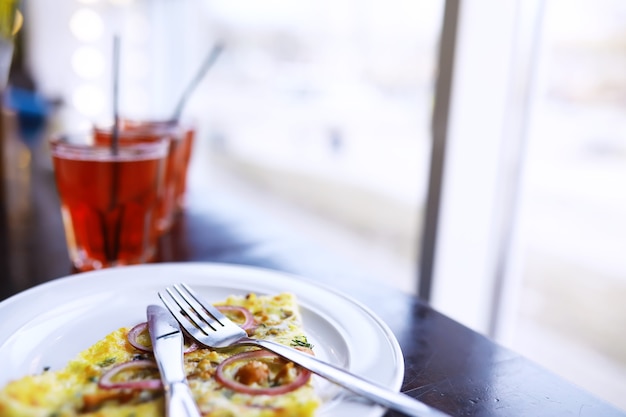 Zbliżenie pizzy bekonowej, soku pomarańczowego w szklance na stole w kawiarni w restauracji