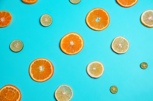 Zbliżenie plasterki cytryny limonki i pomarańczowe owoce w rzędzie na niebieskim tle