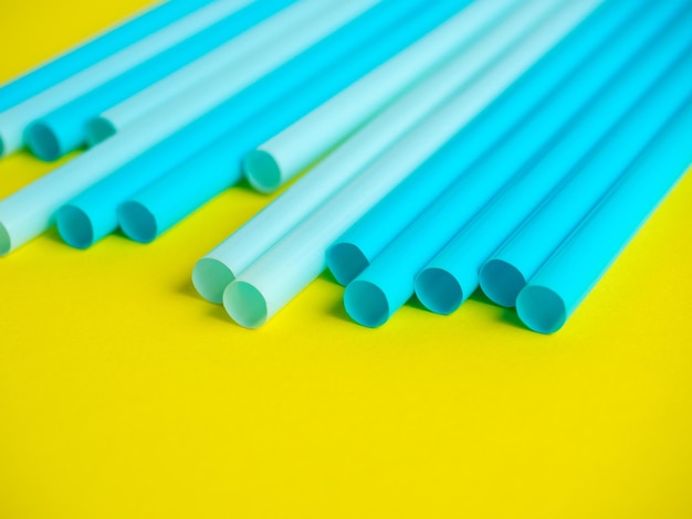 Zbliżenie plastikowych rurek koktajlowych w kolorze niebieskim na żółtym tle