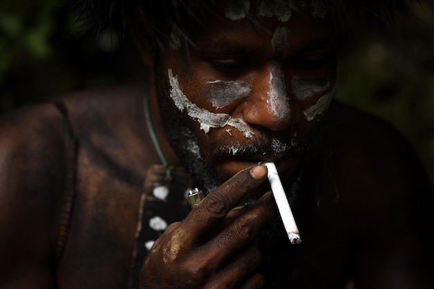 Zbliżenie pomalowanej twarzy Dani plemienia Papua mężczyzna pali papierosa