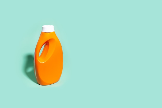 Zbliżenie: pomarańczowa butelka detergentu na tle koloru aqua menthe