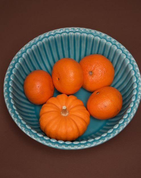 Zdjęcie zbliżenie pomarańczy z dynią w misce na stole