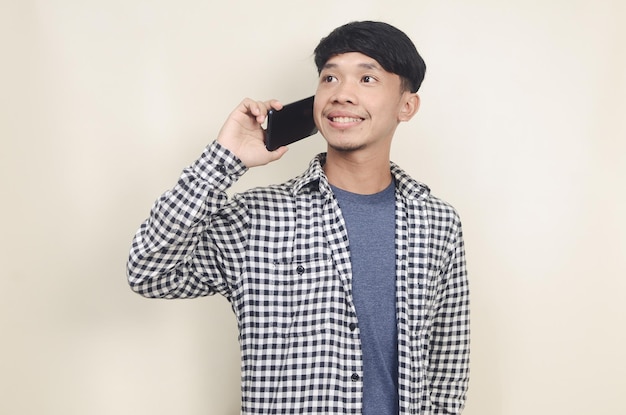 Zbliżenie portret młodego azjatyckiego modelu męskiego na sobie koszulę w kratę, rozmawiając przez telefon
