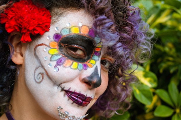 Zbliżenie portret młodej kobiety uśmiecha się patrząc na kamery z makijażem catrina