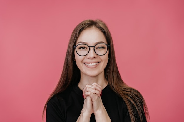 Zbliżenie portret młodej studentki w okularach w czarnej koszulce, która łączy ręce