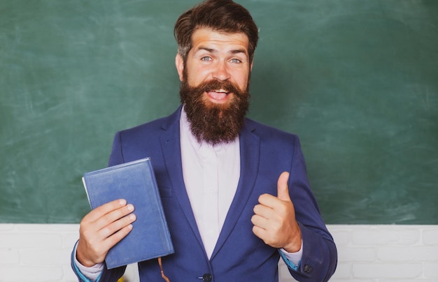 Zdjęcie zbliżenie portret nauczyciela trzymać książkę w szkole na tablicy z miejsca na kopię