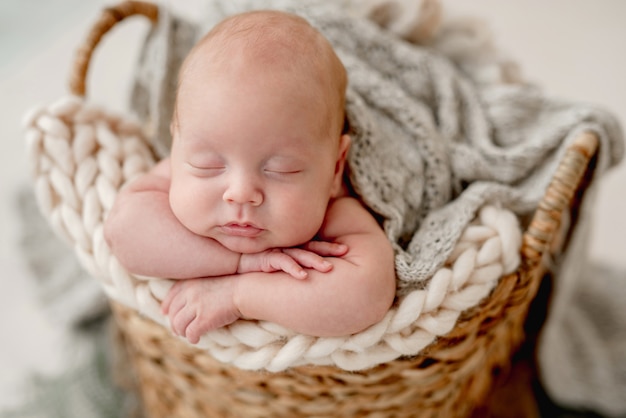 Zbliżenie portret noworodka chłopca, spanie na koc z dzianiny w wiklinowym koszu
