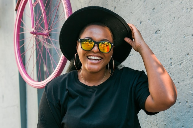 Zbliżenie portret stylowy millenials lub pokolenie z Afroamerykanka z kręconymi włosami w modnych okularach przeciwsłonecznych na miejskich letnich hipsterskich zdjęciach w stylu instagram