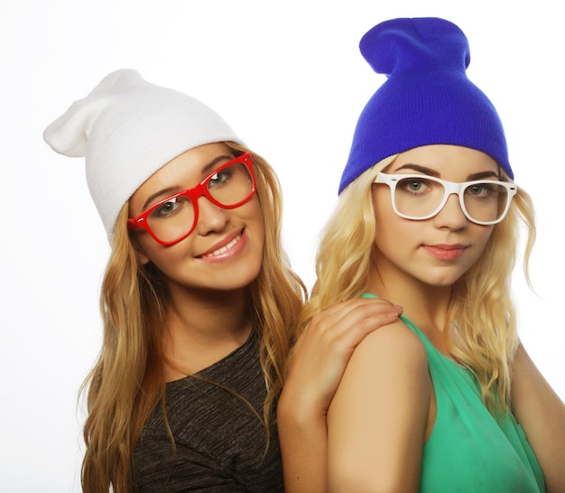Zbliżenie portret stylu życia dwóch ładnych nastoletnich dziewczyn, uśmiechniętych i bawiących się, noszących hipsterskie ubrania w kapeluszach i okularach w pozytywnym nastroju