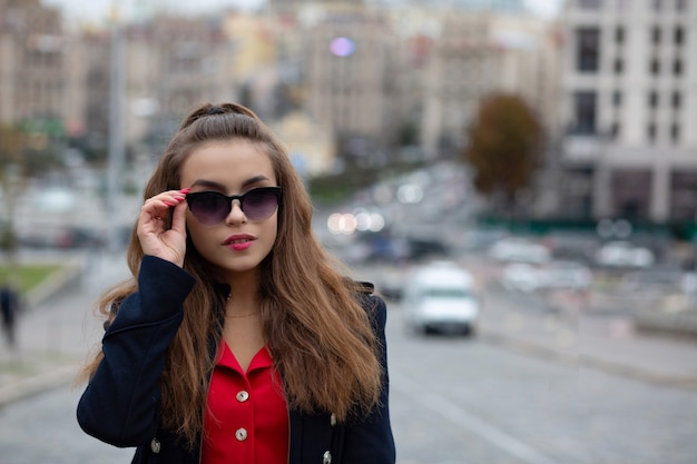 Zbliżenie portret urocza brunetka kobieta w okularach pozowanie w mieście wieczorem. Miejsce na tekst