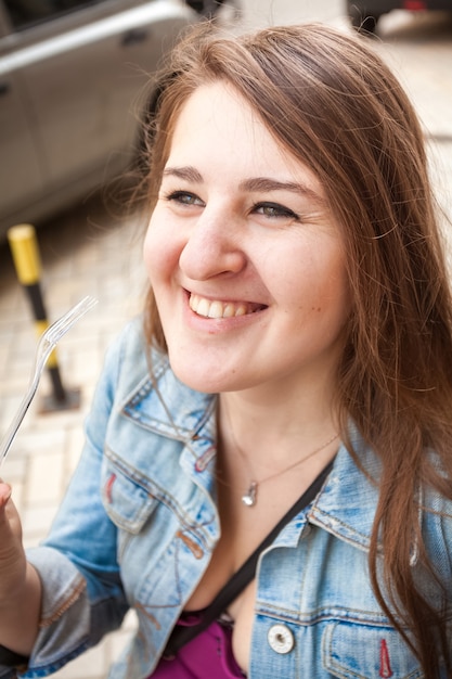 Zdjęcie zbliżenie portret uśmiechnięta młoda kobieta trzyma plastikowy widelec