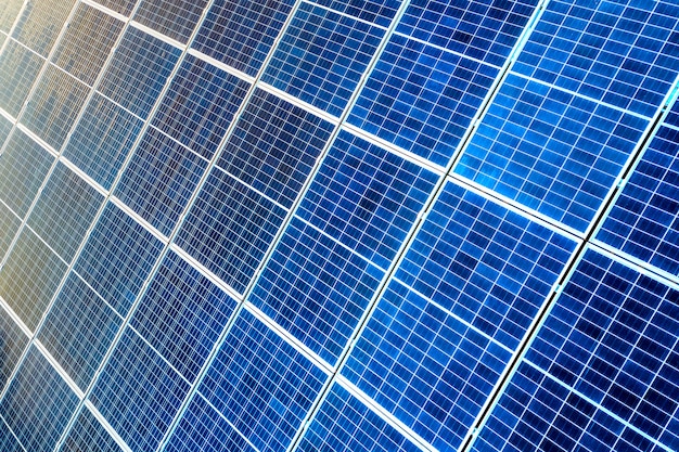 Zbliżenie powierzchni oświetlone przez słońce niebieskie błyszczące słoneczne panele fotowoltaiczne. System produkujący czystą energię odnawialną. Koncepcja produkcji ekologicznej zielonej energii odnawialnej.