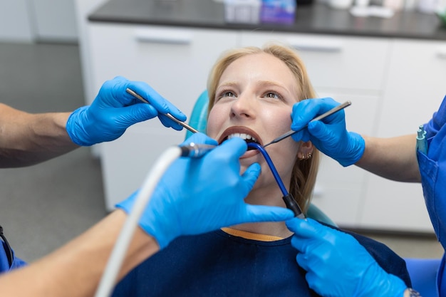 Zbliżenie procedury wiertła dentystycznego u dentysty zbliżającego się do pacjenta z instrumentami dentystycznymi trzymanymi w rękach chronionych rękawiczkami chirurgicznymi