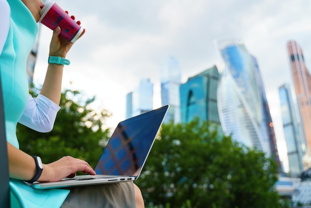 Zbliżenie przycięte zdjęcie kobiety biznesu siedzącej z laptopem na zewnątrz