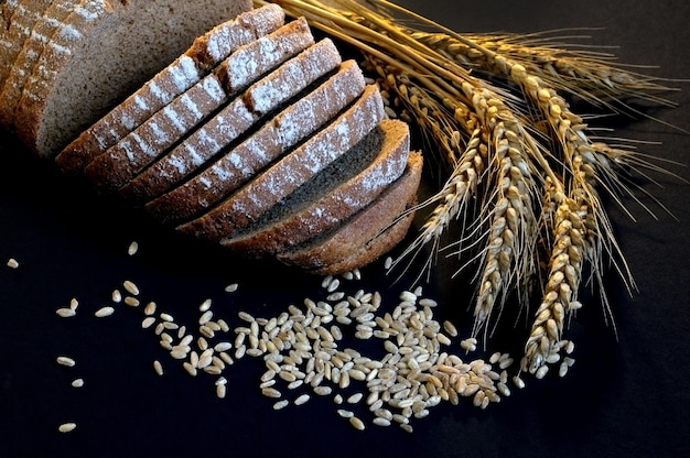 Zdjęcie zbliżenie pszenicy i brązowego chleba na czarnym tle