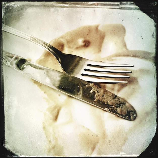 Zdjęcie zbliżenie pustego talerza po posiłku z widelcem i nożem