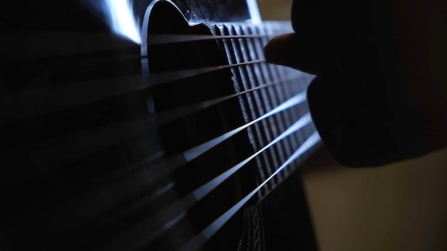 Zdjęcie zbliżenie rąk mężczyzn grających na czarnej gitarze akustycznej koncepcja koncepcja lekcji muzyki