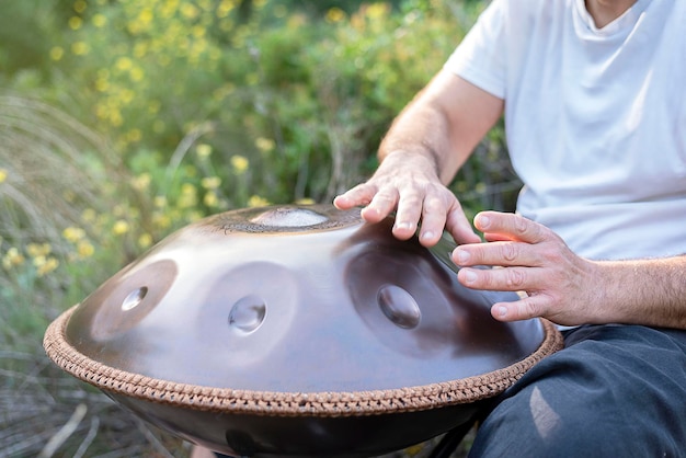 Zbliżenie rąk nierozpoznawalnego muzyka grającego na handpan w przyrodzie