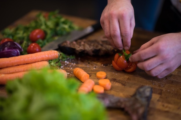 Zbliżenie Rąk Szefa Kuchni W Kuchni Hotelowej Lub Restauracyjnej Przygotowującej Stek Wołowy Z Dekoracją Warzywną