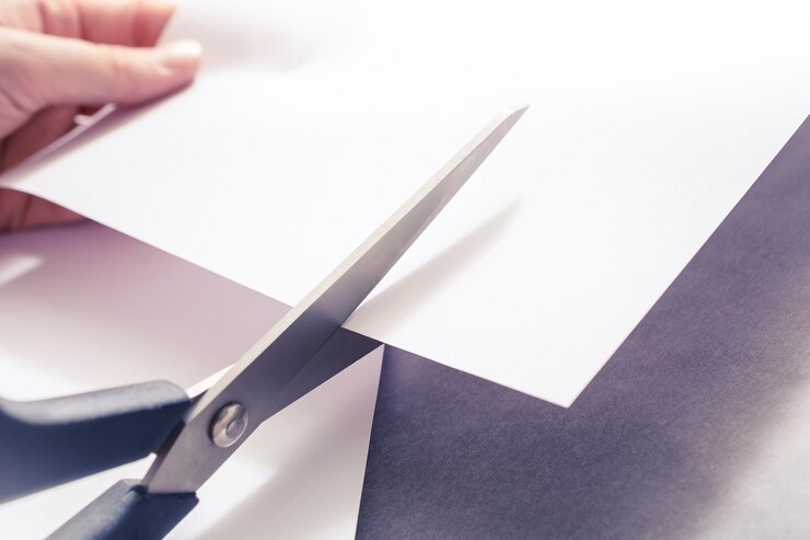 Zdjęcie zbliżenie ręcznego cięcia papieru nożyczkami na stole