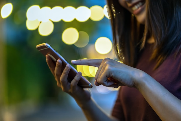 Zdjęcie zbliżenie ręka azjatycka kobieta używa smartphone i macanie ekran przy plenerowym parkiem