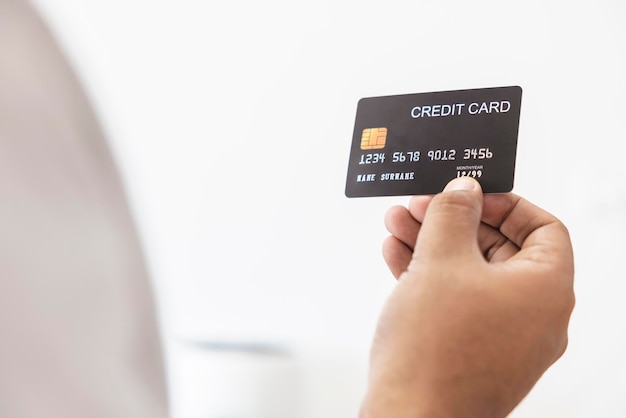 Zbliżenie ręka azjatyckiego mężczyzny trzymającego czarną kartę kredytową w ręku na białym tle Pojęcie finansów handlu komunikacji społecznej technologii biznesu
