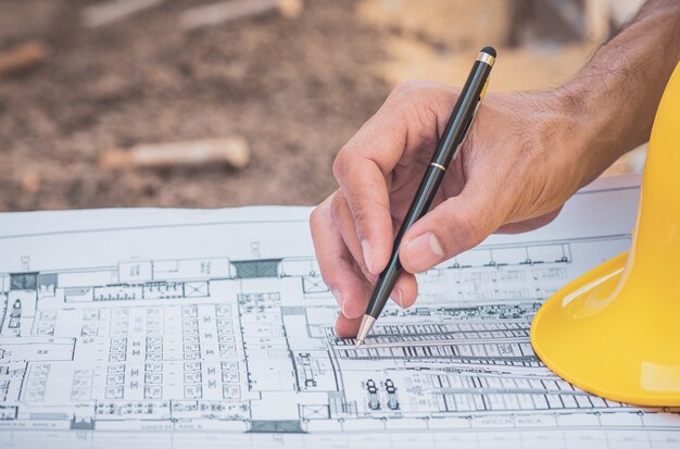 Zbliżenie ręka pisze na projekt papierkowej roboty dokumentu projektanta budynku budowie
