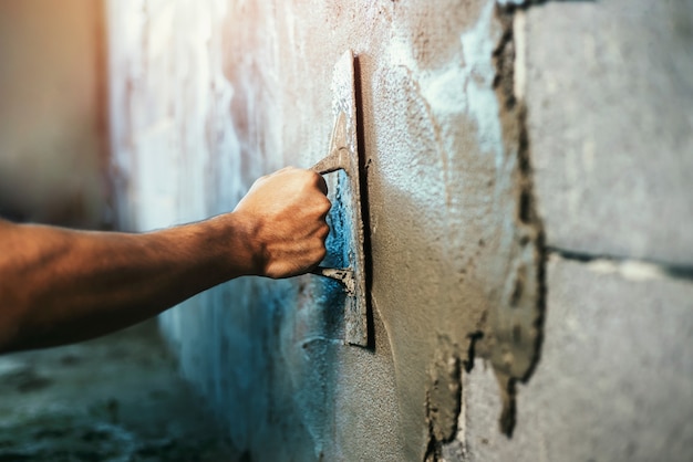 Zbliżenie ręka pracownika tynkowanie cementu na ścianie na budowę domu