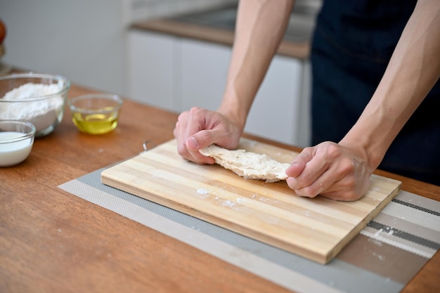Zbliżenie ręka wizerunek męskiego piekarza ugniatającego surowe ciasto robi domowe ciasto w domu