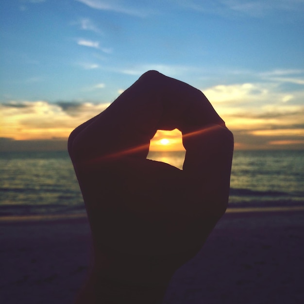 Zdjęcie zbliżenie ręki do morza podczas zachodu słońca