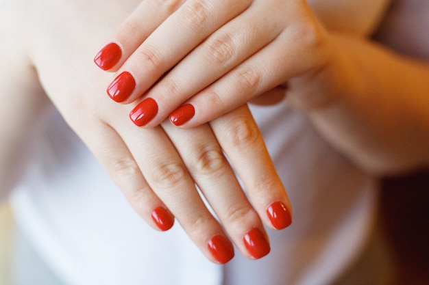Zbliżenie ręki młoda kobieta z czerwonym manicure'em na gwoździach.