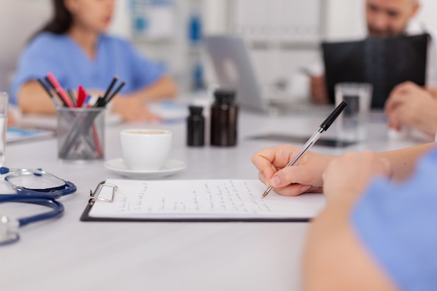Zbliżenie ręki pielęgniarki kobieta analizując badanie lekarskie pisanie leczenia choroby