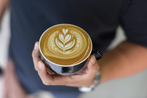 Zbliżenie ręki trzymającej cappuccino