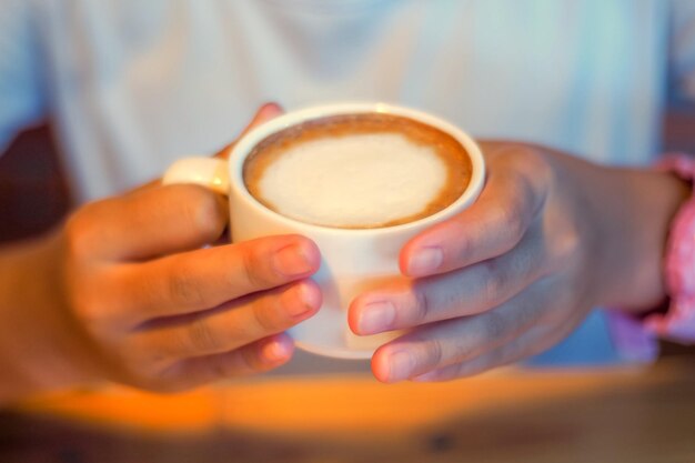 Zbliżenie ręki trzymającej filiżankę kawy