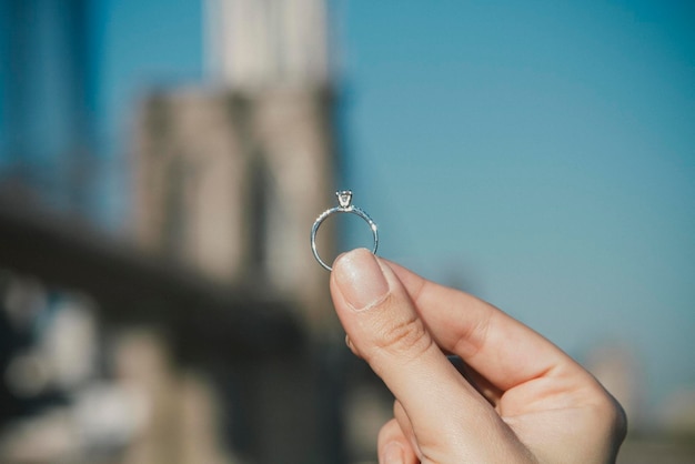 Zbliżenie ręki trzymającej pierścionek ślubny przy Brooklyn Bridge