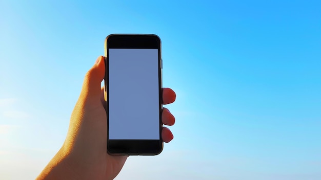 Zdjęcie zbliżenie ręki trzymającej smartfon na tle nieba