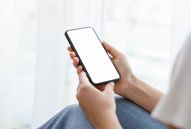 Zbliżenie ręki trzymającej smartphone z białym makieta ekranu.