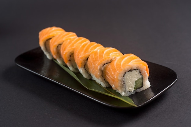Zbliżenie rolek sushi na czarnym talerzu na ciemnym tle