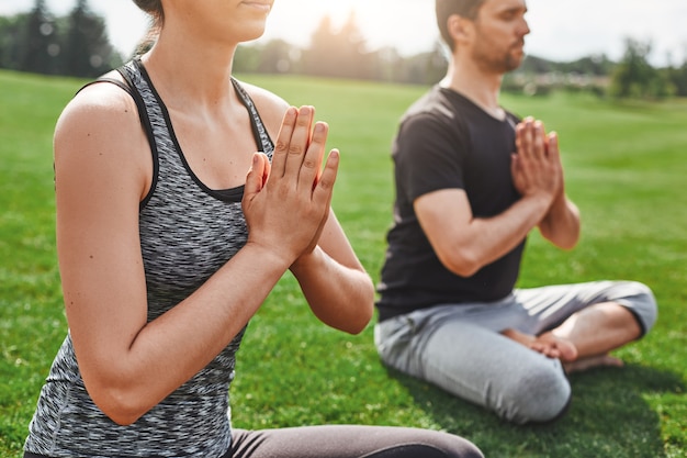 Zbliżenie równowagi życiowej młodej pary medytującej na świeżym powietrzu, siedząc w pozycji lotosu na a